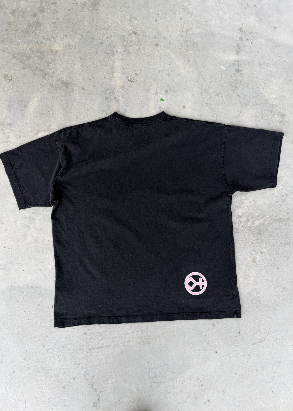 Faded Black + Rose | Black t-shirt with a pink logo on a concrete floor